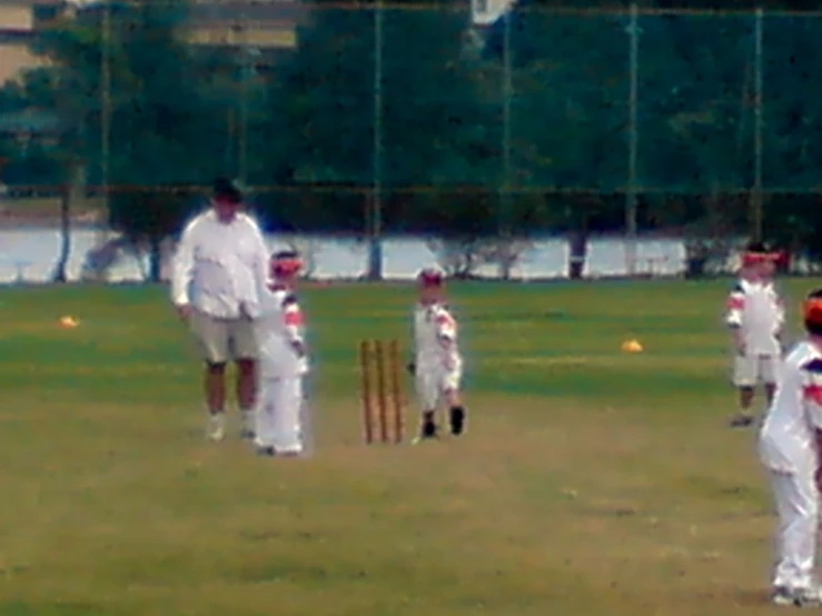 several children and a man are playing a game of cricket