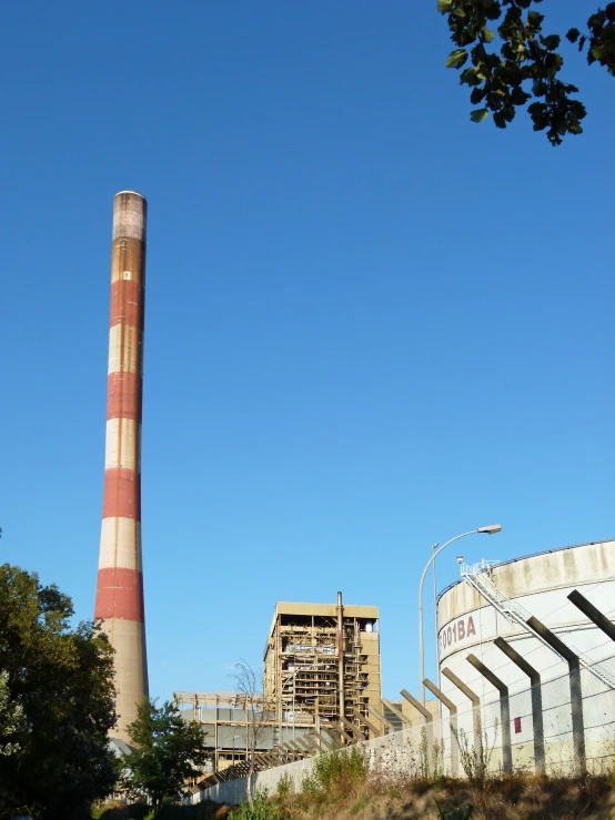 an industrial factory that has a tower and a pipe in front