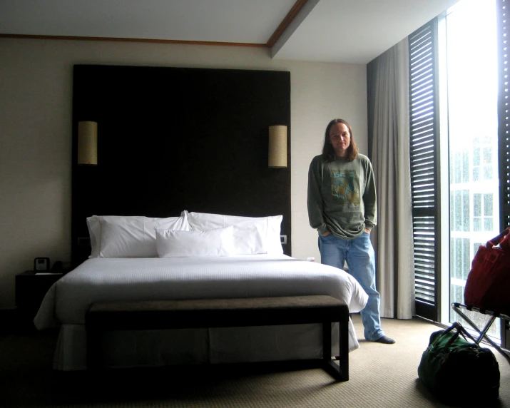 a man standing in front of a bed next to a window