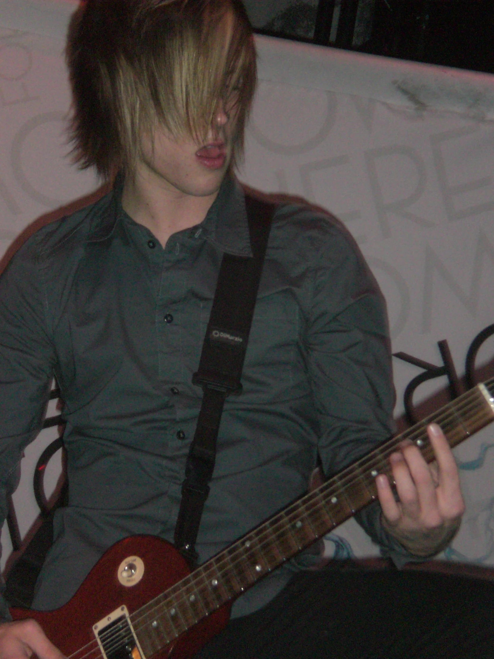 the young man is playing his guitar in the room