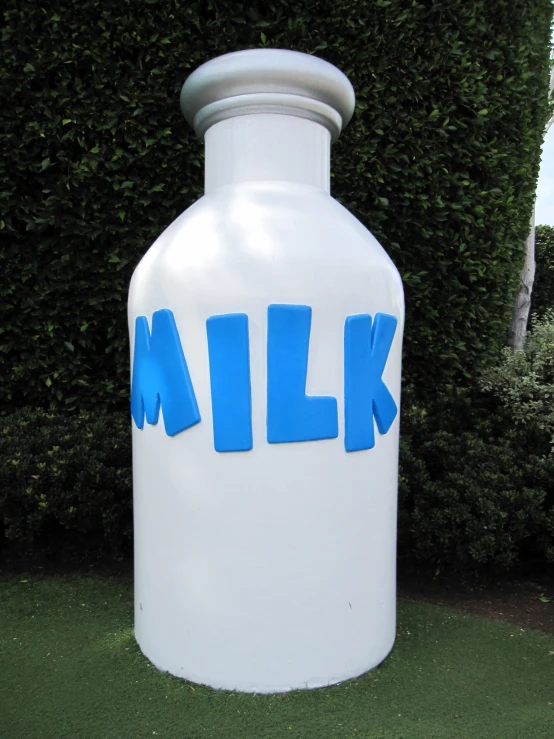 an outdoor milk can sculpture that has the word milk written on it