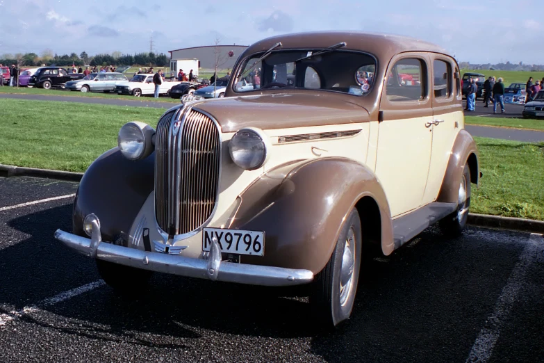 old car sitting in a parking lot with a bunch of cars