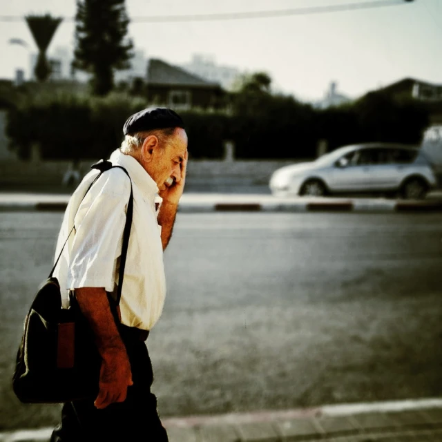 a man walking on the street with his cellphone to his ear