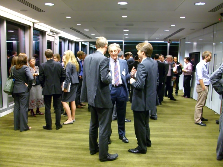 several people standing and talking while in an office corridor