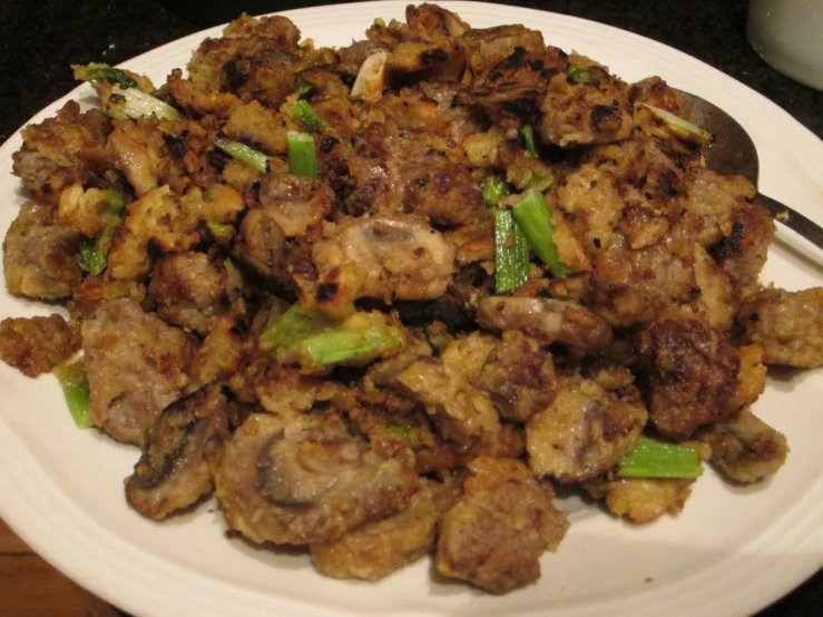 a white plate topped with meat and green onions