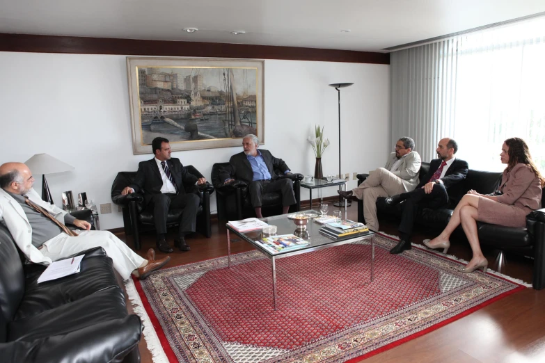 group of business people sit in a room in front of windows