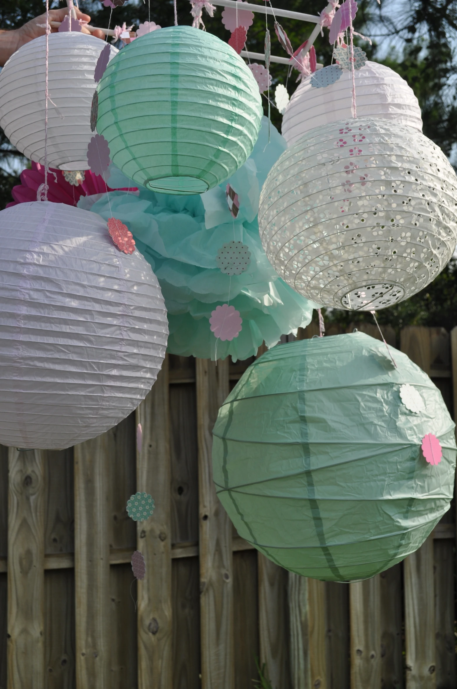 four paper lanterns hang from chains that are hung outside