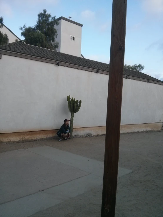 a man is sitting on the sidewalk by the building