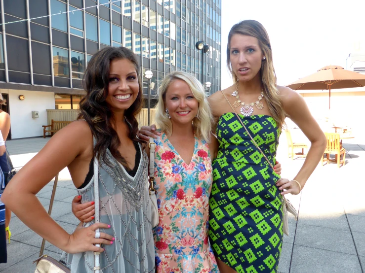 three beautiful women posing for the camera in front of a building