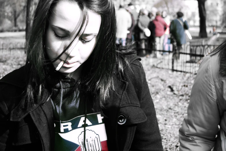 a woman smoking a cigarette standing next to a group of people