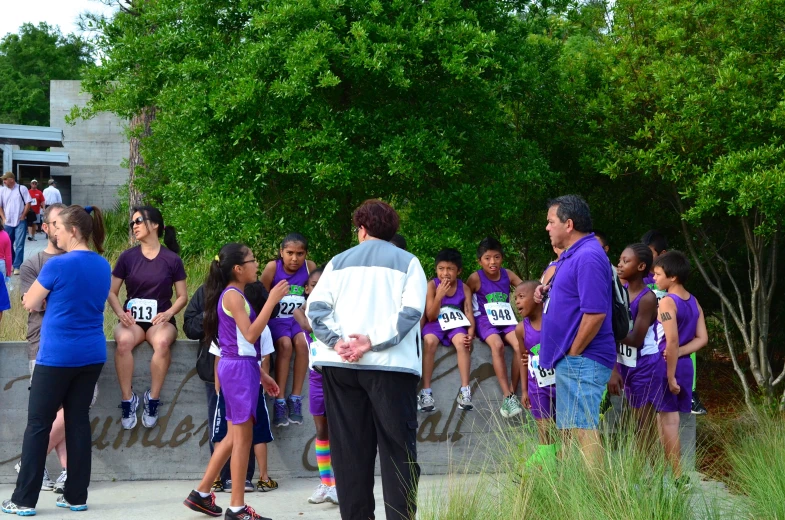 the race runners are wearing purple clothes and some are carrying water bottles