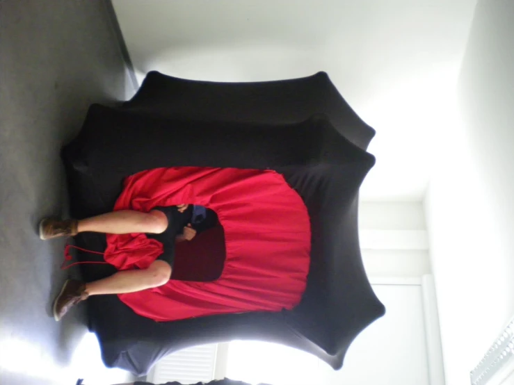 there is a woman wearing a red dress standing under an umbrella