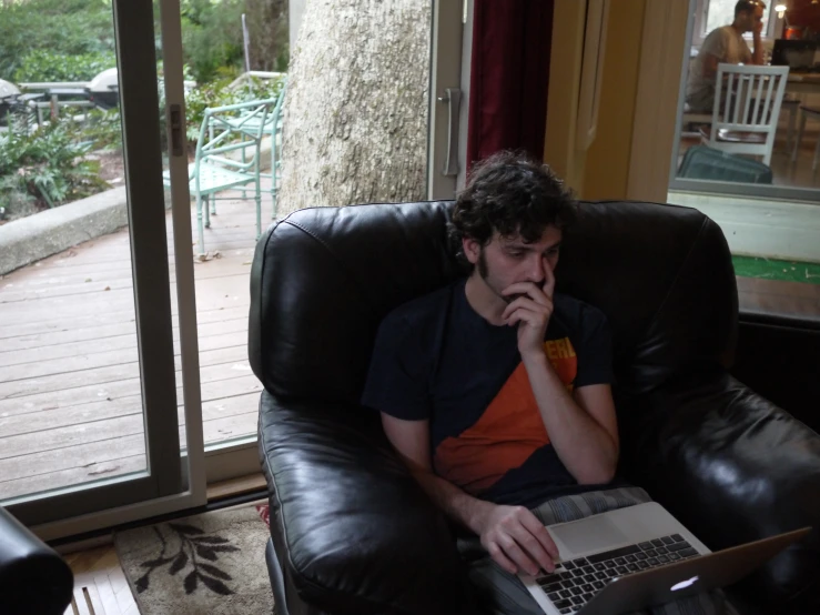 a young man sitting in a chair with a laptop computer