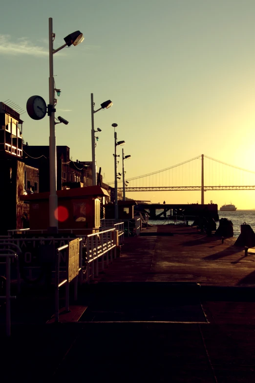 sunset on a waterfront by the water with the sun setting behind the bridge