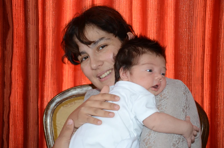 a woman holding a baby while sitting in a chair