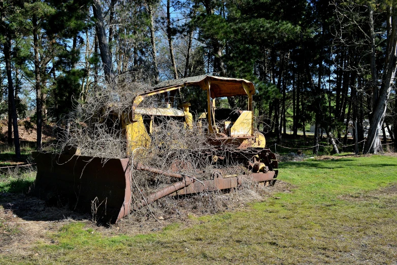 a large bulldozer in the middle of a grassy area with trees in the background