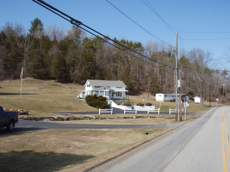 an older white house and farm near a road