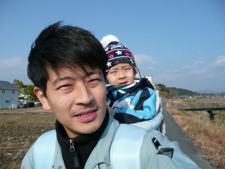 a man holding a child with a house in the background