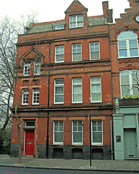 an old brick building sits on the corner with trees in front of it