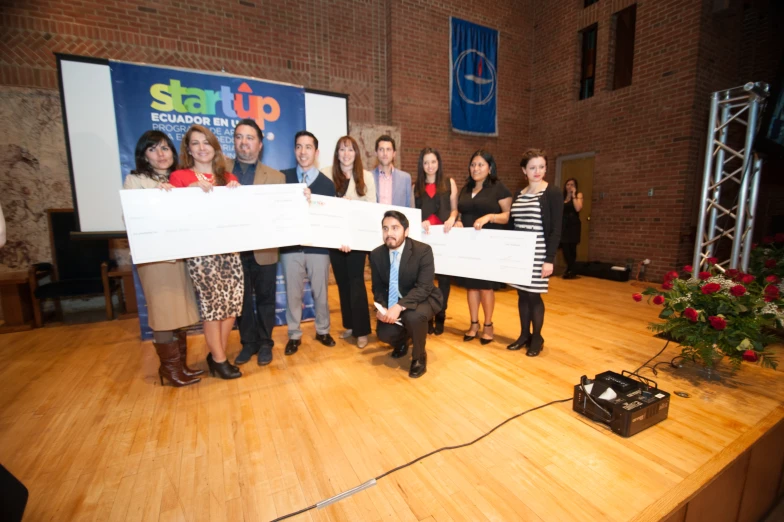 a group of people standing on top of a stage holding large cheque checks