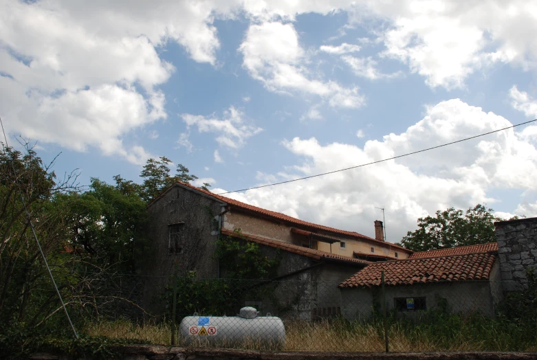 an abandoned house is shown with clouds in the background