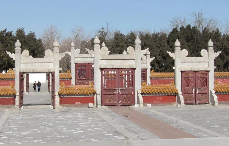 two people walking away from a row of red and white gates