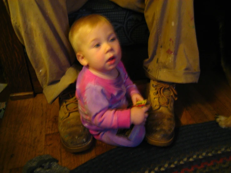 an adorable little girl wearing a pink top sitting in a pair of brown boots