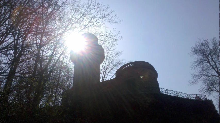 the sun shining down from behind a brick building