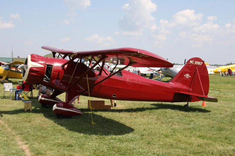 a red plane with two propeller sitting on some grass