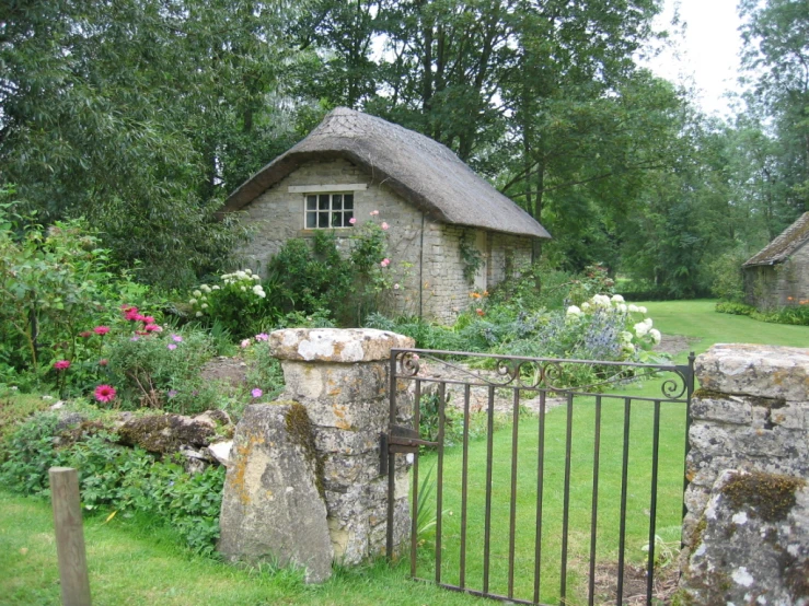 an old, stone building surrounded by flowers and foliage