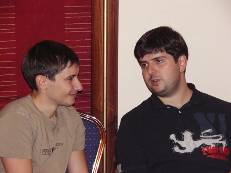 a young man sitting next to an older man talking