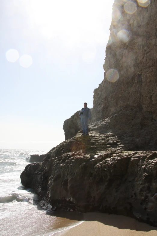 man on the edge of an ocean cliff looking at the water