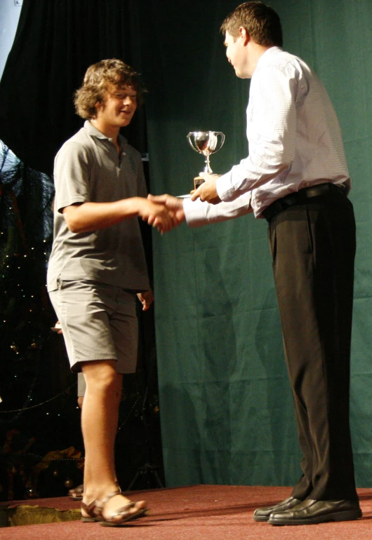 two men are shaking hands while holding a glass