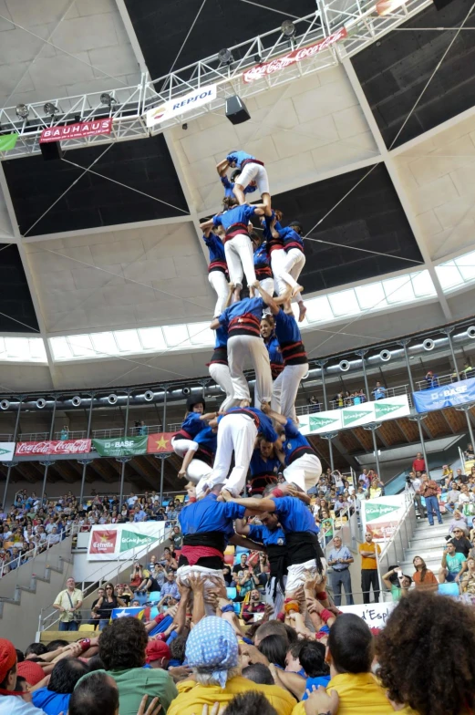 a crowd watches as a group of people are balancing in the air