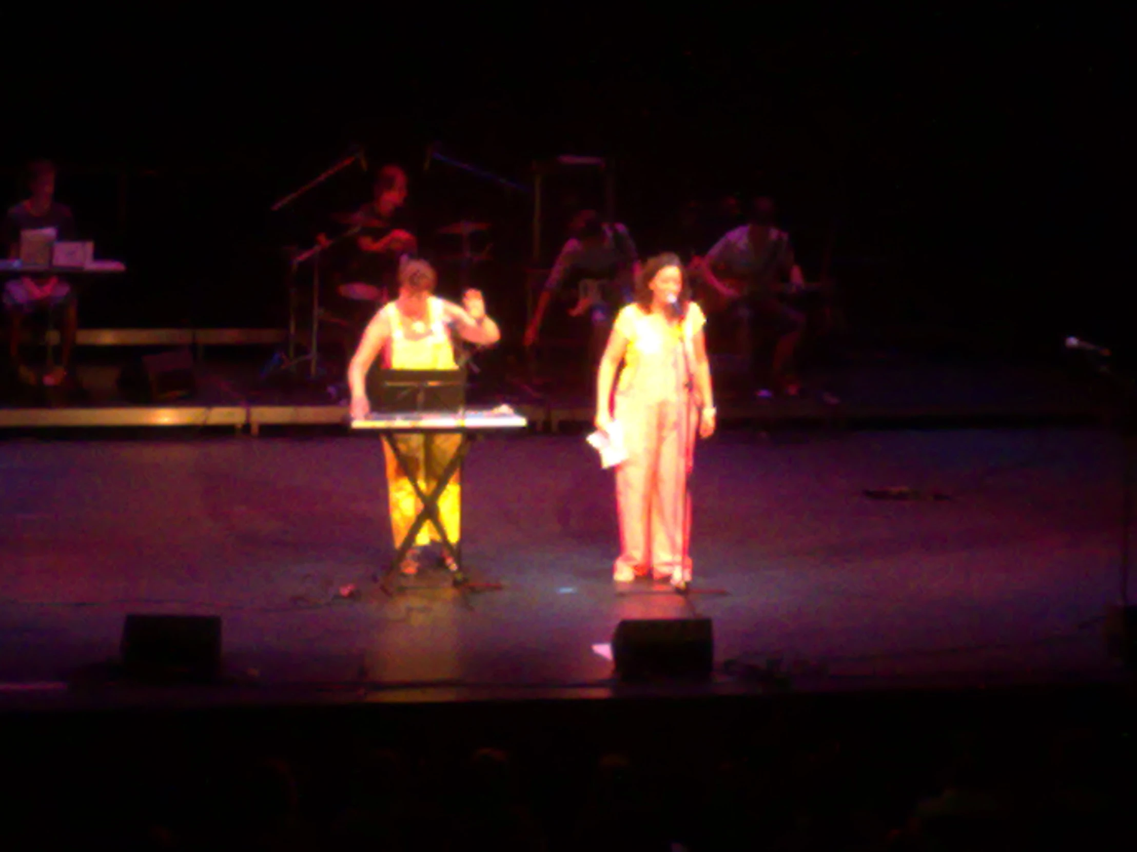 two performers on stage with music playing behind them