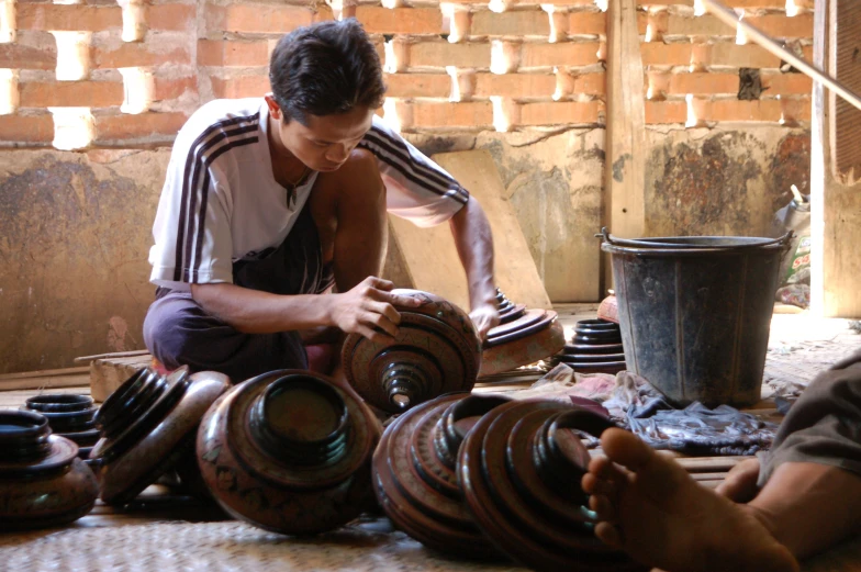 two men are working on various vases together