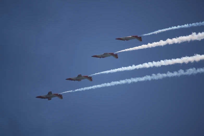 four jet fighter planes flying in formation with smoke billowing out from their tails