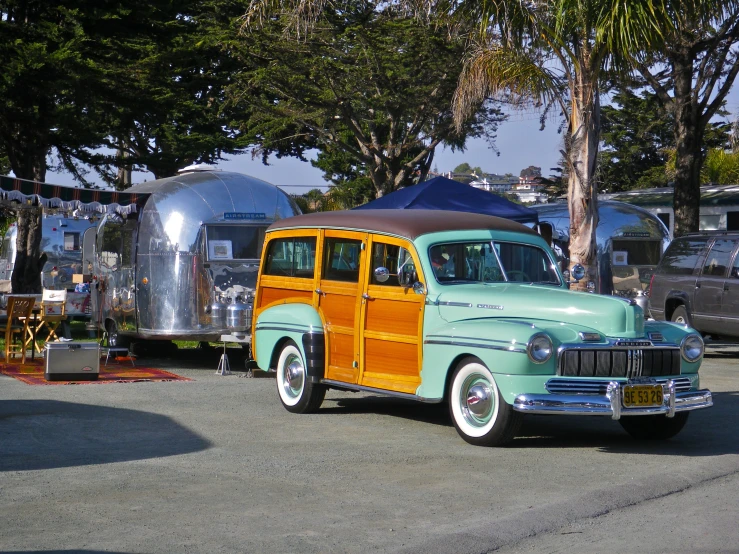 an old classic station wagon with wood paneling parked in front of other trailers