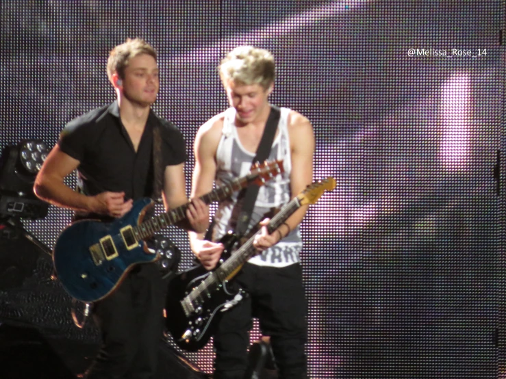 a man plays guitar next to another man on stage