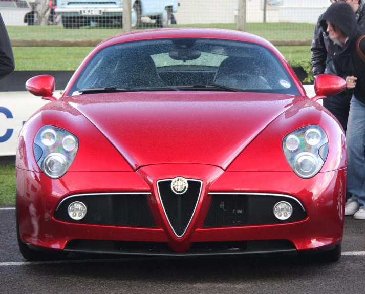 a red sports car with two people standing in the background