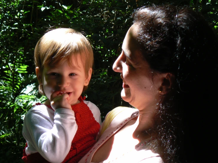 a woman holds a small child in the sunlight