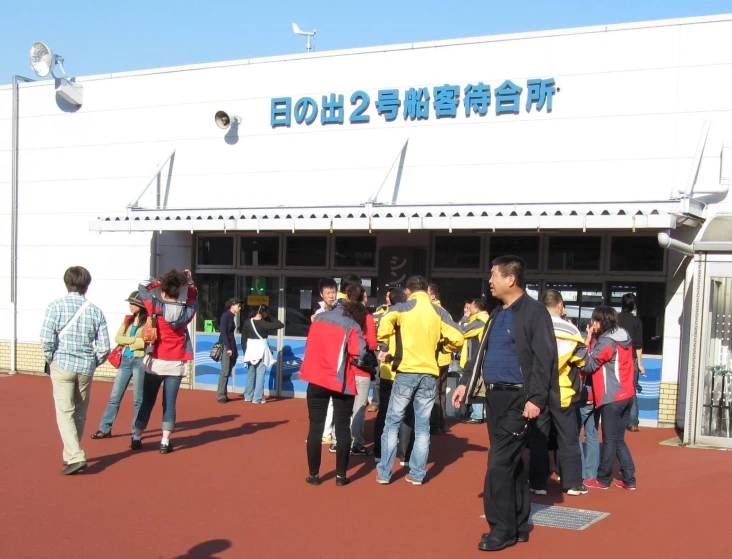 group of people waiting outside a building, with a sky background