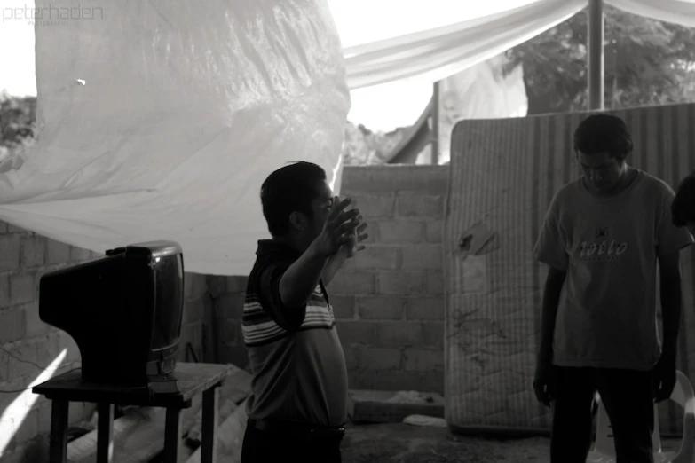 three people standing in a tent and one is holding a phone