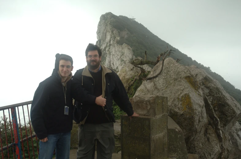 two men are posing in front of some large rocks
