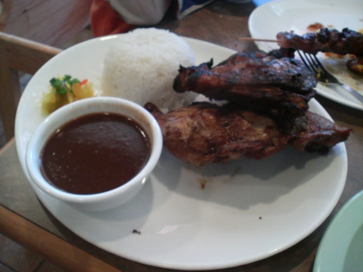 food on a plate with meat, rice, and red wine