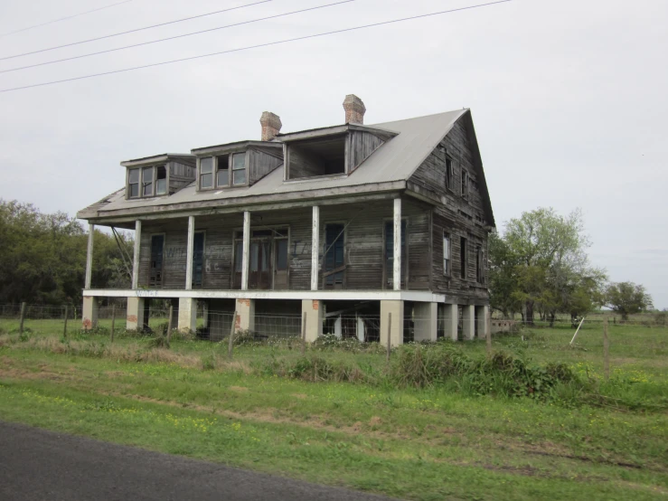 an abandoned house in a field on the corner of a road