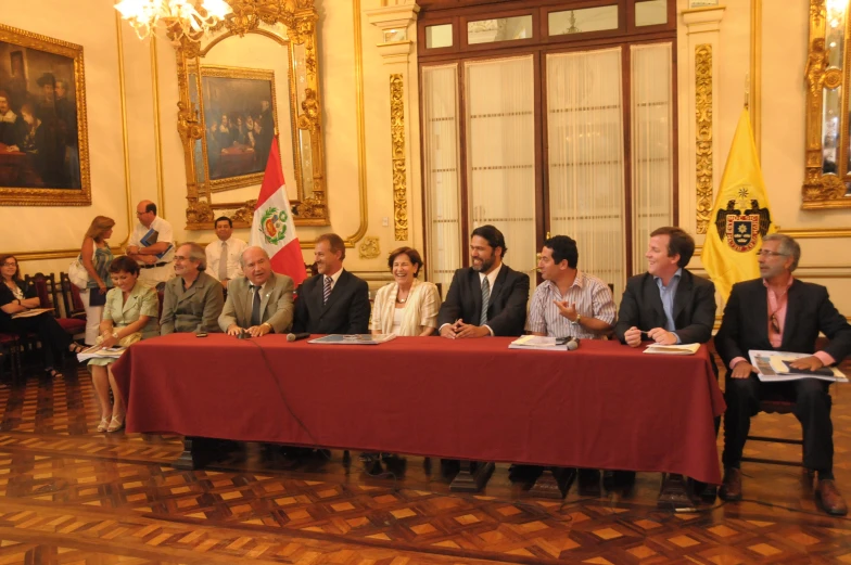 several people sitting at a table while one man is talking