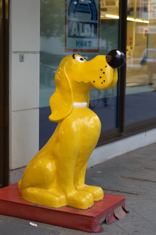 a large yellow dog statue sitting outside a business