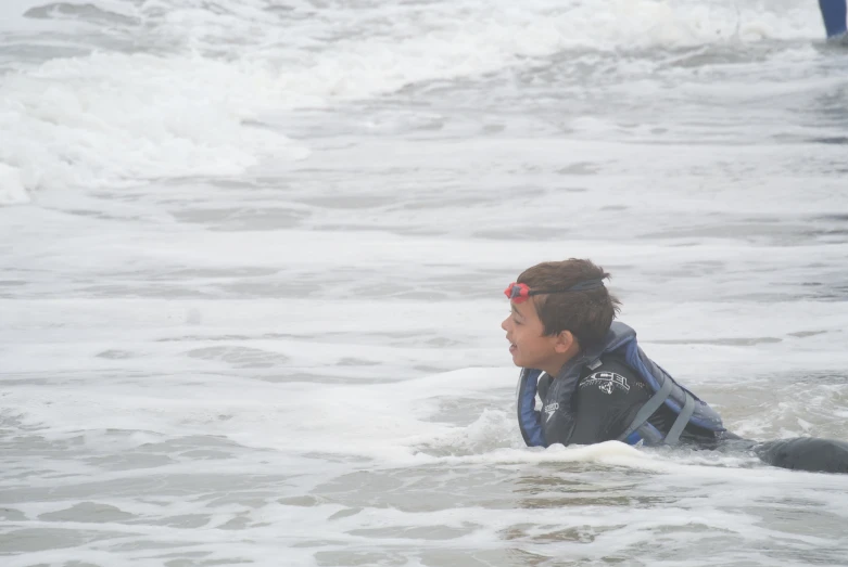 a boy in goggles on his surfboard at the beach