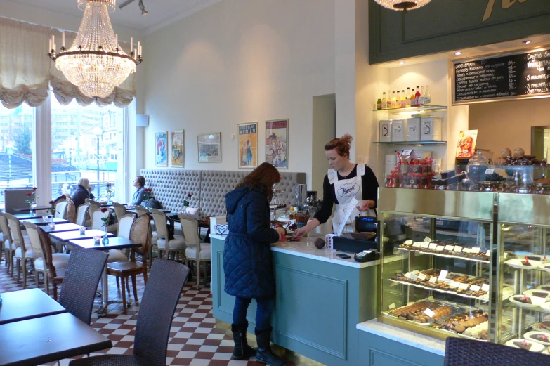 there are two woman standing at the counter of the bakery